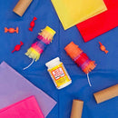 Colorful paper crafts and Mod Podge bottle on a blue surface